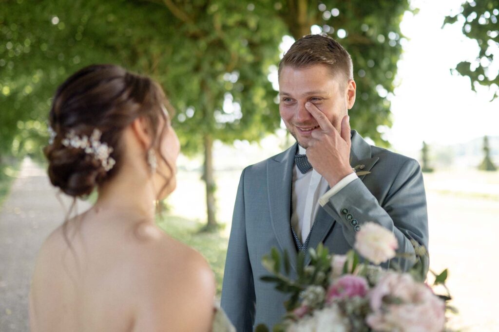 Bräutigam wischt sich beim First Look auf Schloss Hundisburg eine Träne aus dem Auge