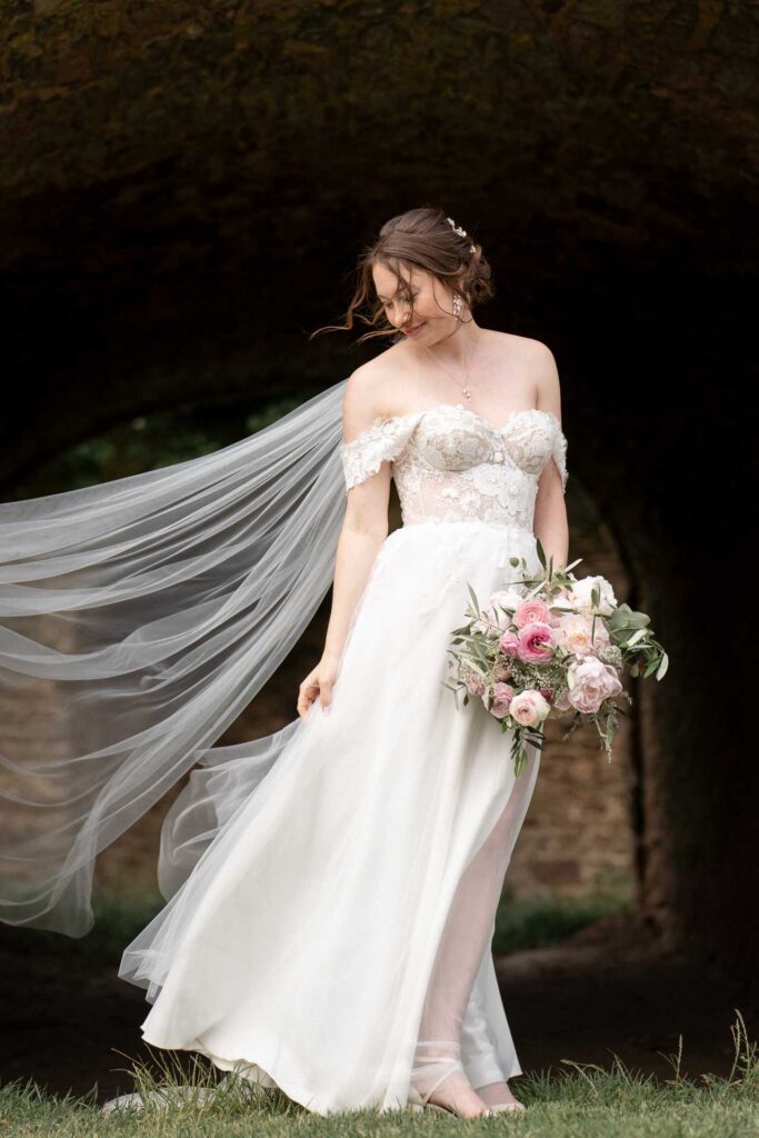 Braut im Schlosspark von Hundisburg blickt lächelnd auf ihr Brautkleid